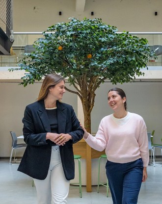Smiling students from the INSEEC business school in front of the orange tree in the hall of the Rennes campus